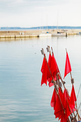 Fototapeta na wymiar Red marina flags by water