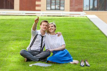 Fototapeta premium young couple sitting on the grass at the business center during a