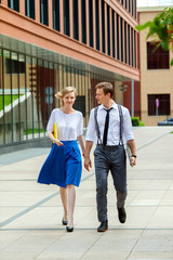 A two modern young people are walking along office building