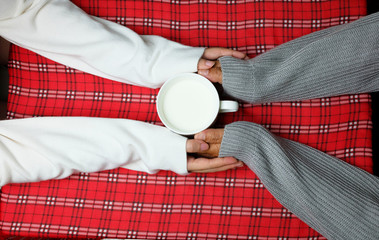 Hand holding on winter with warm drink on red table cloth