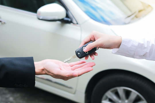 Closeup of a female car owner giving car keys from the car dealer.