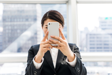 Fototapeta premium young businesswoman taking a picture with smart phone
