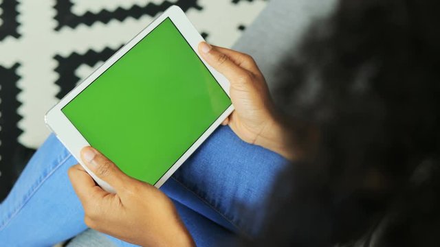 African American woman hands holding the white tablet computer with the green screen. Horizontal. Chroma key. Top view. Textured background