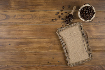 Coffee bean grain and sack fabrice board on brown wood table background , include copyspace for add text or graphic in advertise or marketing content