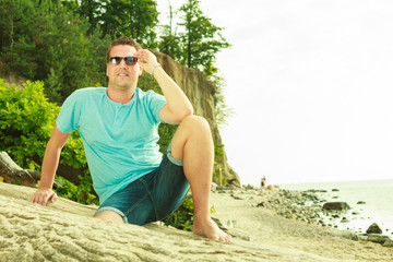 Naklejka na ściany i meble Handsome man relaxing on beach during summer.