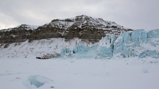 Glacier of beautiful unique turquoise color on background of snow in Arctic. Amazing ice desert landscape. Silence quiet of wilderness North Pole Way to Pyramid on Spitsbergen Svalbard in Norway.