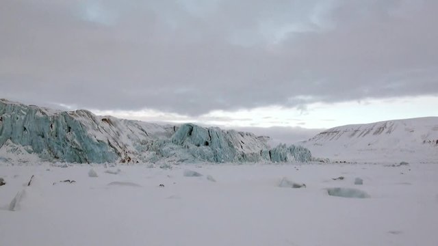 Glacier of beautiful unique turquoise color on background of snow in Arctic. Amazing ice desert landscape. Silence quiet of wilderness North Pole Way to Pyramid on Spitsbergen Svalbard in Norway.