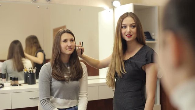 Young woman make-up artist tells a make-up technique for a group of girls. Master class for make-up artists.
