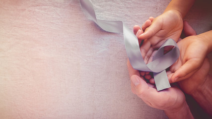 Adult and child hands holding Light blue, sky blue ribbons, toning background, Prostate Cancer Awareness and Adrenocortical carcinoma awareness