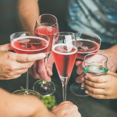 Holiday celebration table setting. Friends hands drinking together. People having party, gathering, celebrating with rose champaign