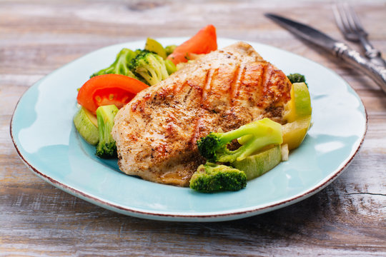 Grilled turkey fillet with vegetables on blue plate. Healthy meal concept