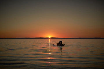 Boat in the sea with two fishermen in it, nets in the sea. Sunset or sunrise