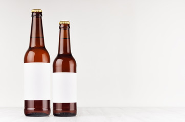 Brown beer bottles longneck 500ml and 330ml with blank white label on white wooden board, mock up. Template for advertising, design, branding identity.