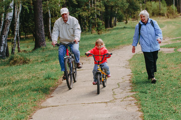 Naklejka premium active seniors teaching granddaughter to ride bike