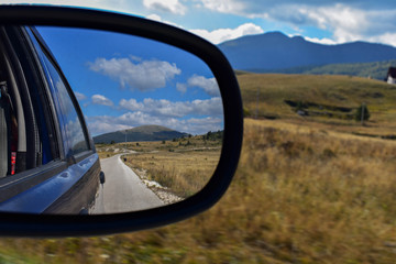 rear view car driving mirror view green forest road and mountain