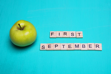 First september. Conception with apple and inscription on blue background.
