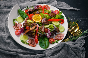 Salad with bacon and chicken liver. On a wooden surface. Top view. Free space for your text.