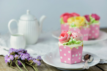 Vanilla cup cake and spoon on a plate with cup cake in background and flower  as decoration for valentine,s day,  mother's day or birthday.