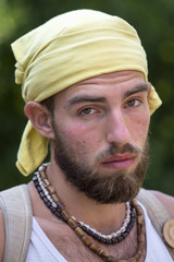 Portrait of young man in a kerchief with a beard relaxing on the nature in summer day