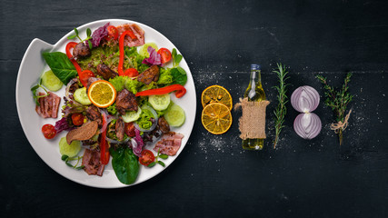 Salad with bacon and chicken liver. On a wooden surface. Top view. Free space for your text.