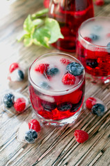 Summer berry lemonade with frozen berries on a wooden rustic table, selective focus