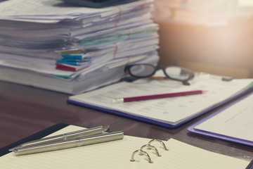 Business and finance concept of office working, Pile of unfinished documents on office desk, Closeup pen and pencil with stack of business paper