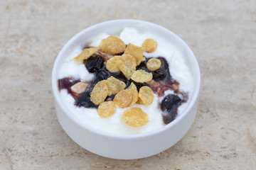 White bowl with muesli, berry, flakes, yogurt and honey, close up