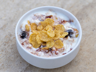 White bowl with muesli, berry, flakes, yogurt and honey, close up