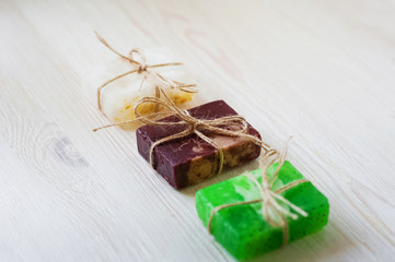 A white, brown and green piece of soap tied with a rope and nestled on a white tree. Spa accessories. Sprigs of a Christmas tree, many multi-colored pieces of soap, many different shapes of bottles fo