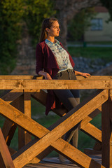 beautiful girl on a wooden bridge at sunset