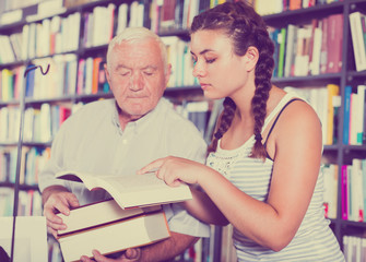 Old man with young granddaughter are reading books