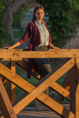 beautiful girl on a wooden bridge at sunset