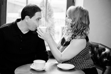 Middle age couple in love sitting in a cafe, drinking coffee, having a conversation and enjoying the time spent with each other. Joyful loving mature couple resting at home at winter morning