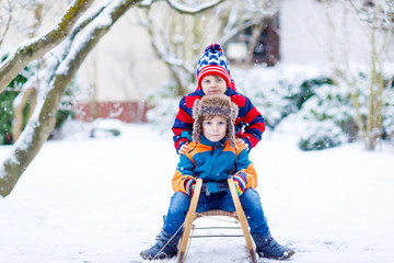 Fototapeta na wymiar Two little kid boys enjoying sleigh ride in winter