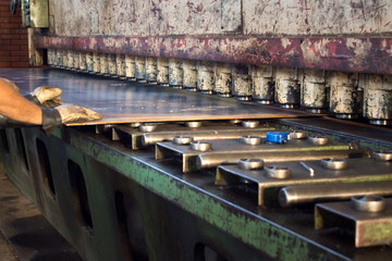 Workers inserting metal plate into compression machine