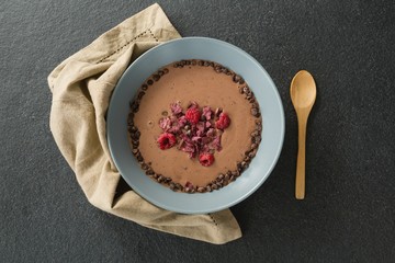 Chocolate syrup with fruits in bowl on black background