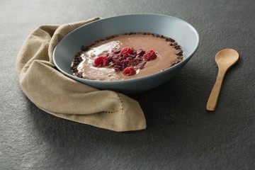 Chocolate syrup with fruits in bowl on black background