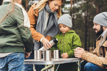 mother pouring tea from thermos for kids