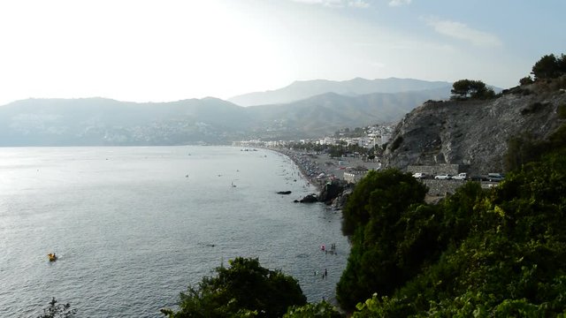 Landscape of mediterranean beach with mountains and people bathing in summer
