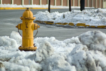 A fire hydrant sits amidst a snowy and polluted street scene.
