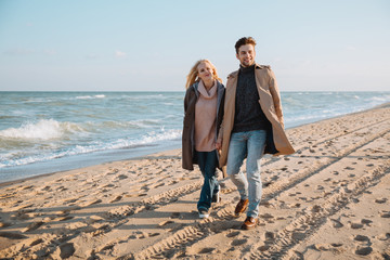 couple walking on seashore in autumn