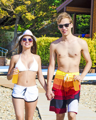 Jolly youthful couple enjoying summer drinks on resort