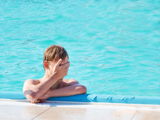 Man in the swimming pool. Teenager hides the face in hands in the pool. Concept of wound and trauma.