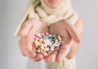 Many multi-colored pills in a woman hands on white background;