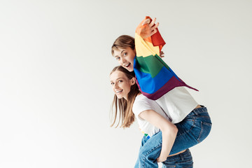 Woman giving piggyback to girlfriend with flag
