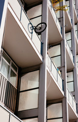 A bicycle hangs out of an apartment balcony.