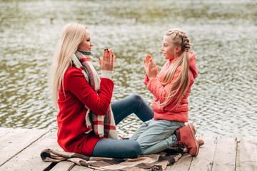 mother and daughter sitting near lake