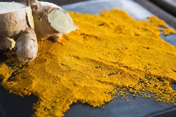 Turmeric powder and ginger on board