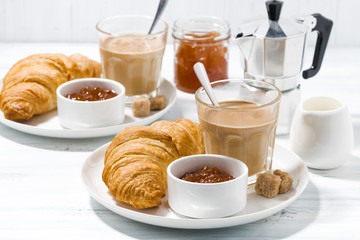 coffee with milk and croissants with jam for breakfast on white table