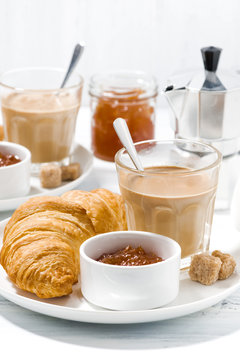 coffee with milk and croissants with jam on white table, vertical closeup